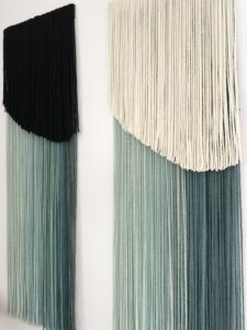 Set of two handmade wall hangings crafted from hand-dyed merino and sheep wool in green and cream tones.