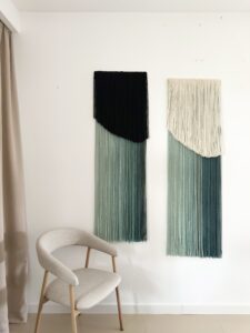 Set of two handmade wall hangings crafted from hand-dyed merino and sheep wool in green and cream tones.